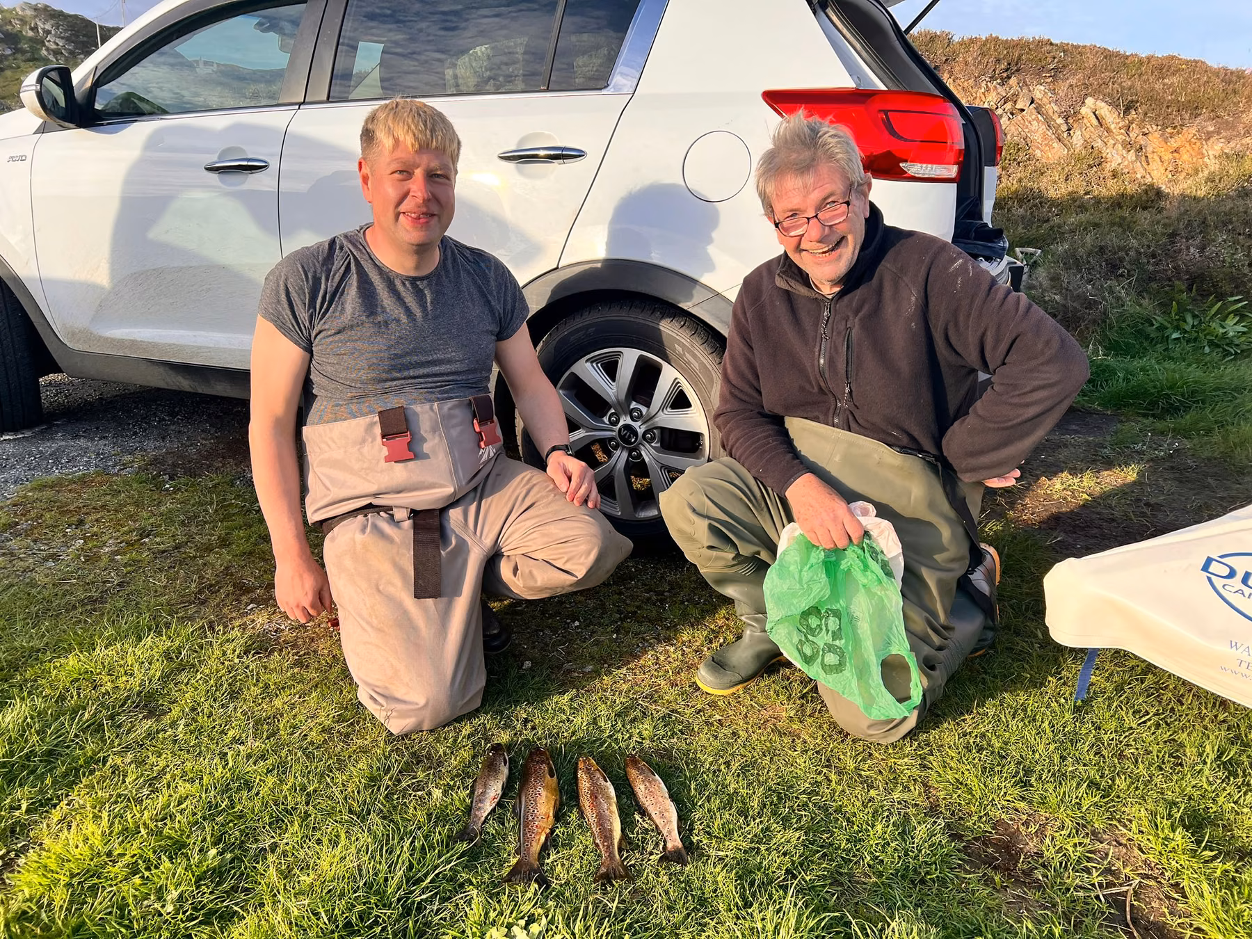 Two anglers with their catch by the car